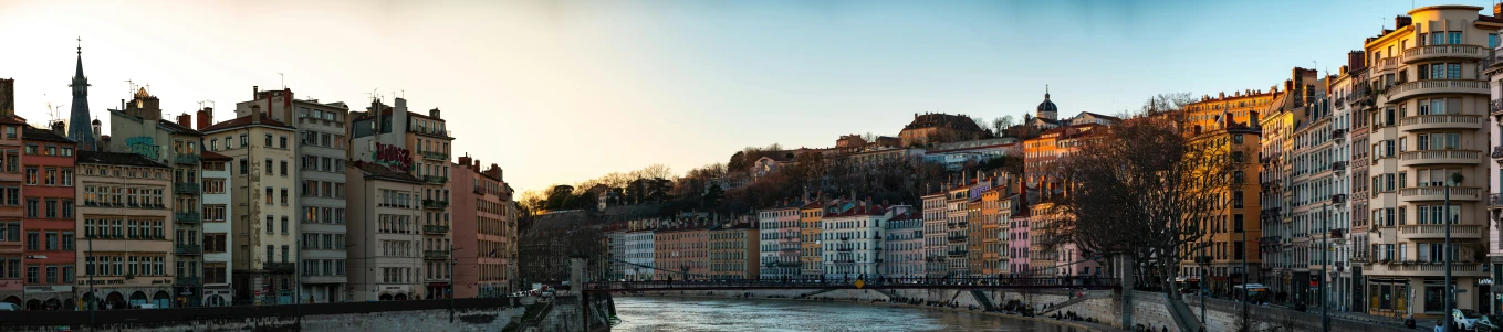 the sun shines over a group of old buildings on a river