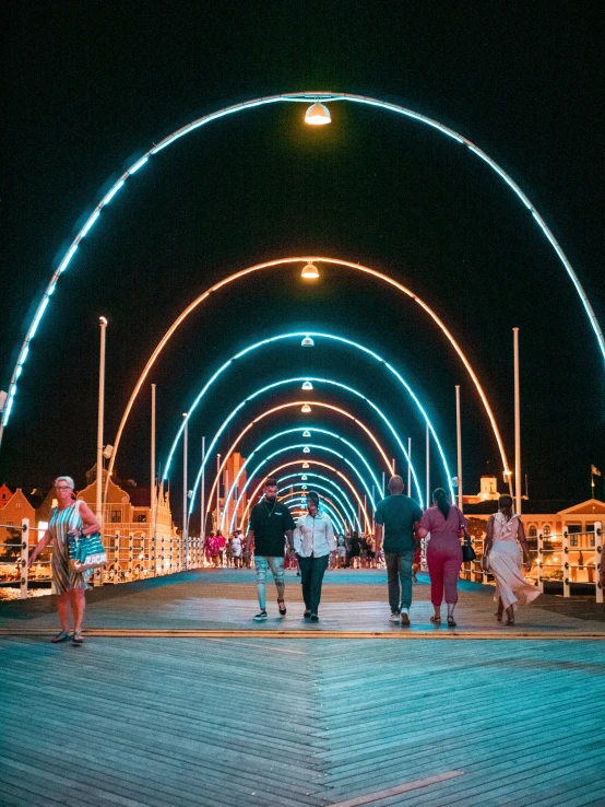 people walking through an archway with lights on at night