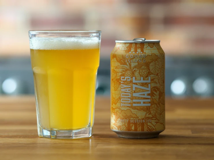 a glass and can of beer sit on a table