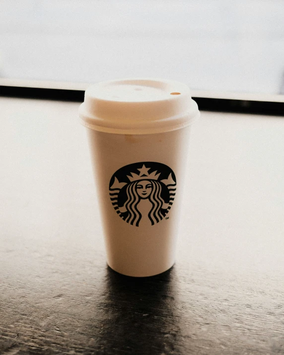 a starbucks coffee cup with a brown lid on top