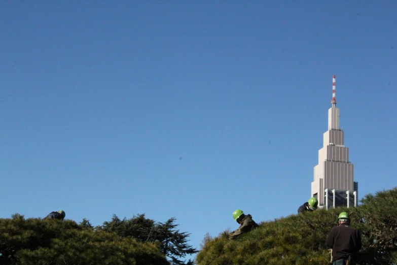 three people at the top of the steeple with the spire in the background