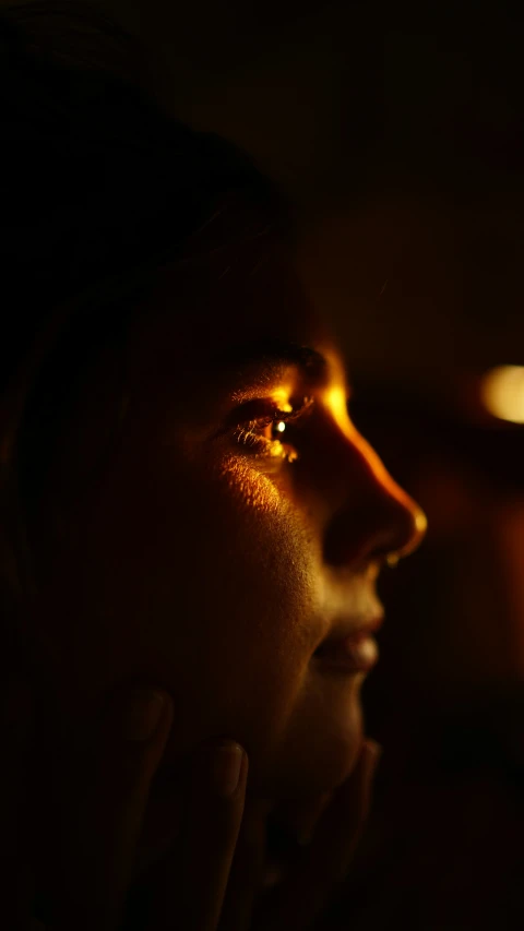 a girl in the dark with her hand under her face and one side is lit up