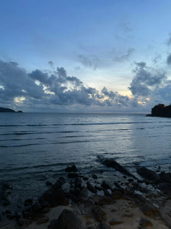 the water is calm and clear as a person stands on a beach