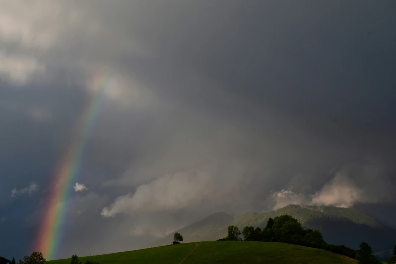 a large rainbow in the middle of a cloud filled sky