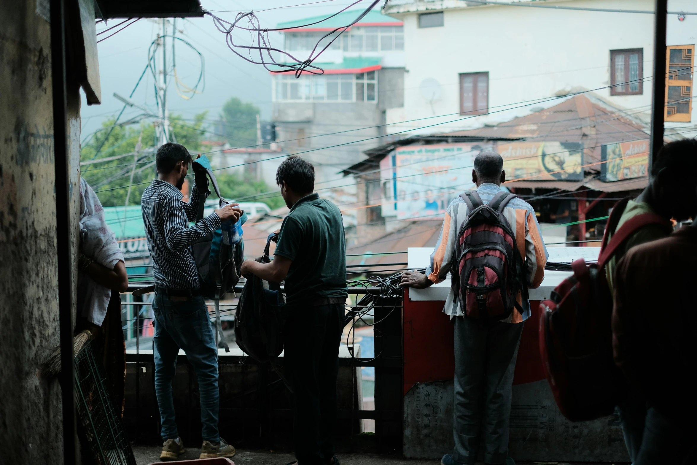 men looking out at the city while one has his back turned to his camera