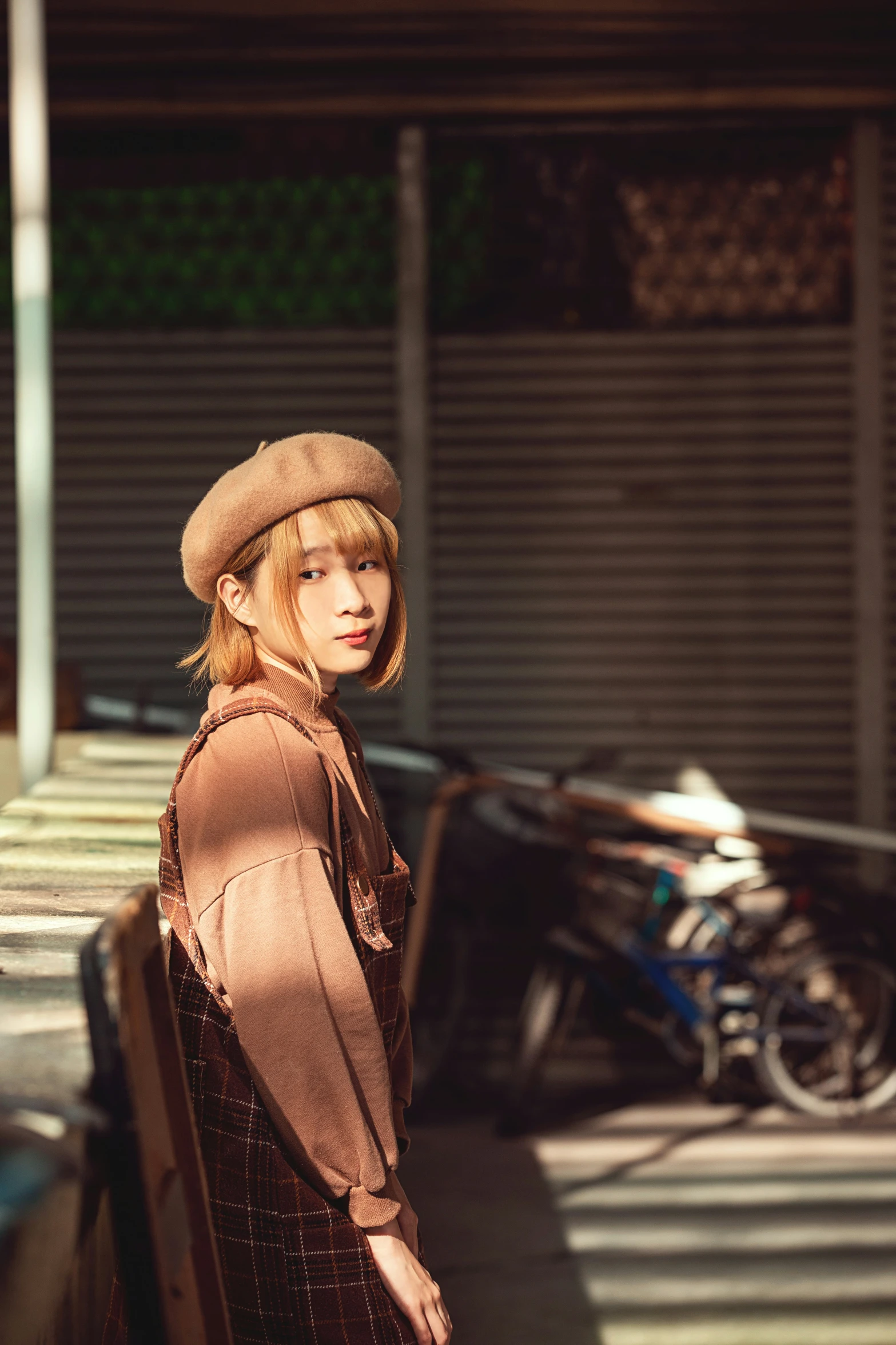 a woman standing next to a building with a motorcycle behind her