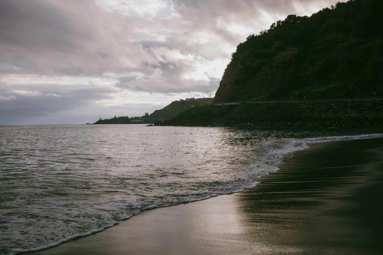 water is coming towards a rocky shore on a cloudy day