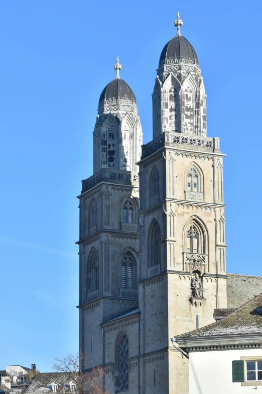 a church with tall spires sitting next to a tree