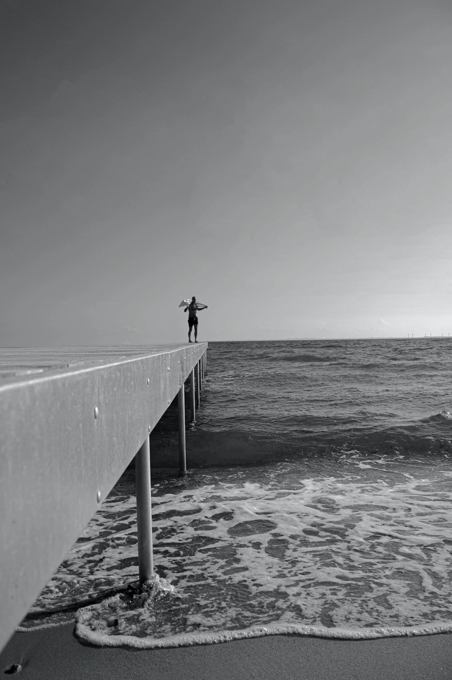 the man is standing on the side of the pier looking at the water