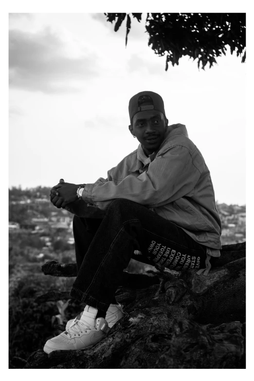 black and white po of man sitting on rock