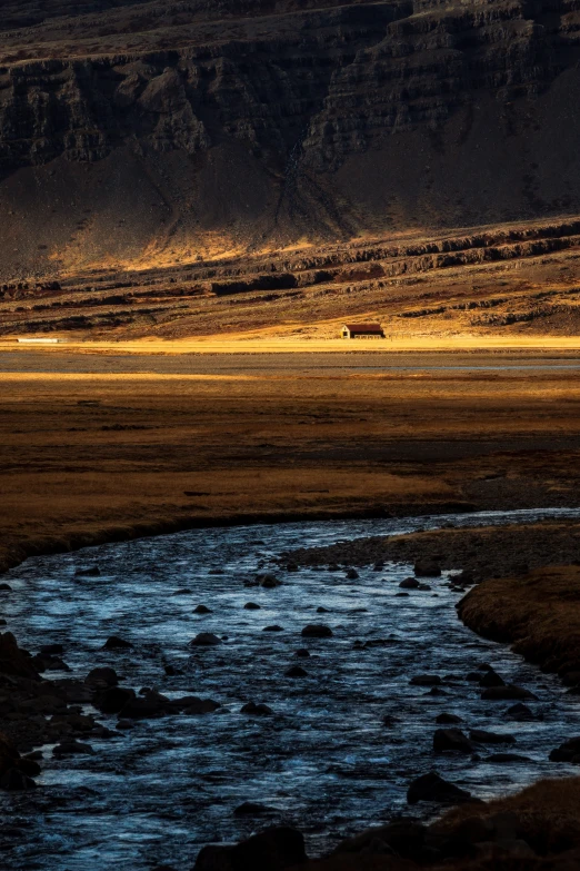 a stream of water in a field with mountains in the background