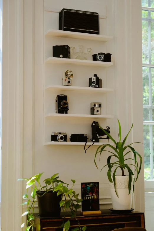 a collection of various electronics and cameras on a white shelf