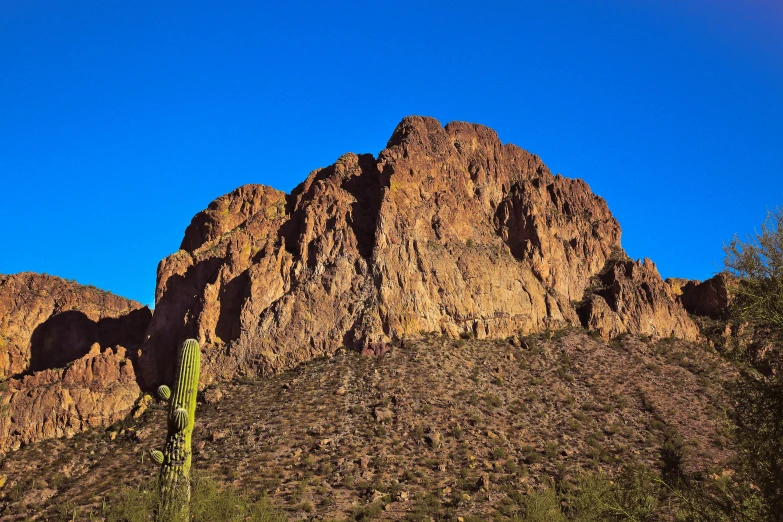 there are three mountains in the desert with a cactus in the foreground