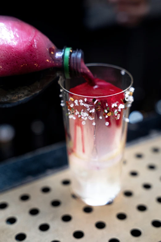 a red drink is poured into a glass