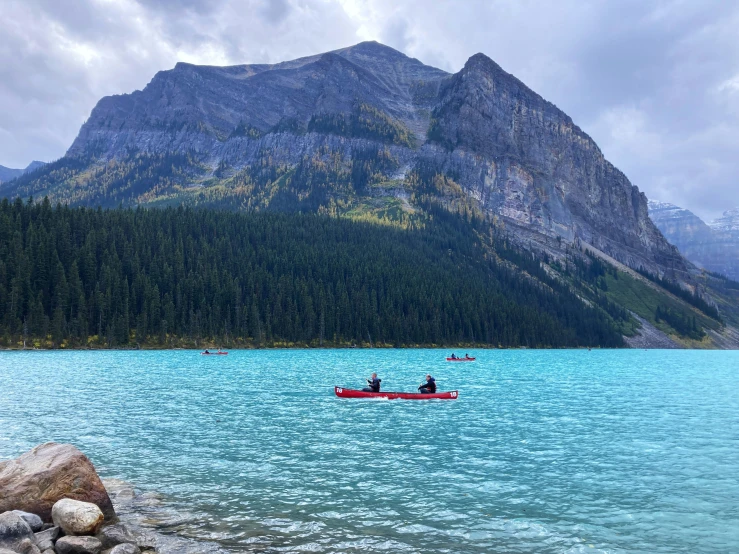 a man in a kayak on the water by mountains