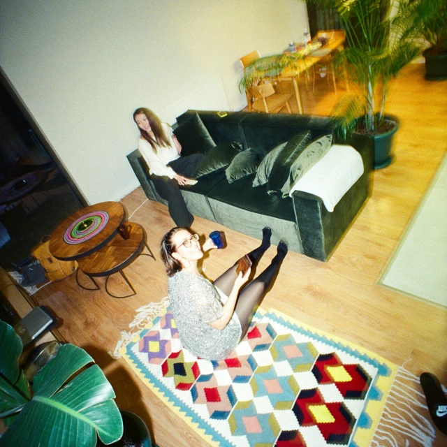 two young women sitting in an apartment setting, one on a chair