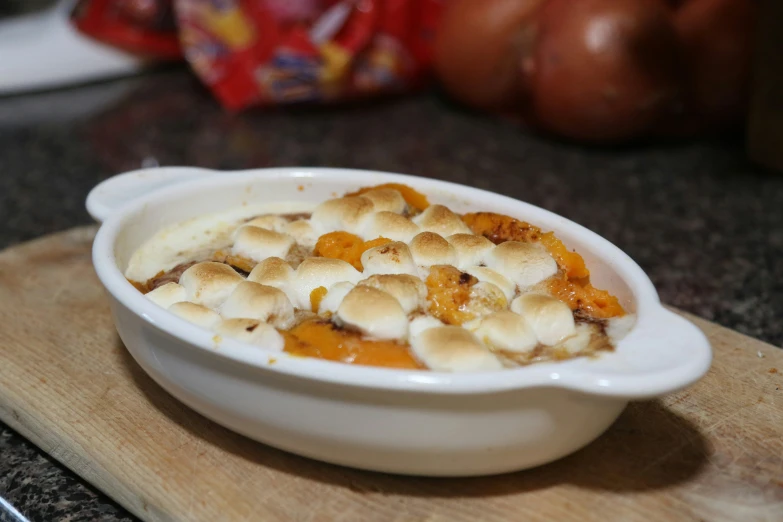 a dish of fruit ding on top of a wooden  board