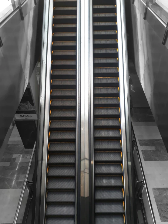 an escalator at the top of a flight with some metal railing