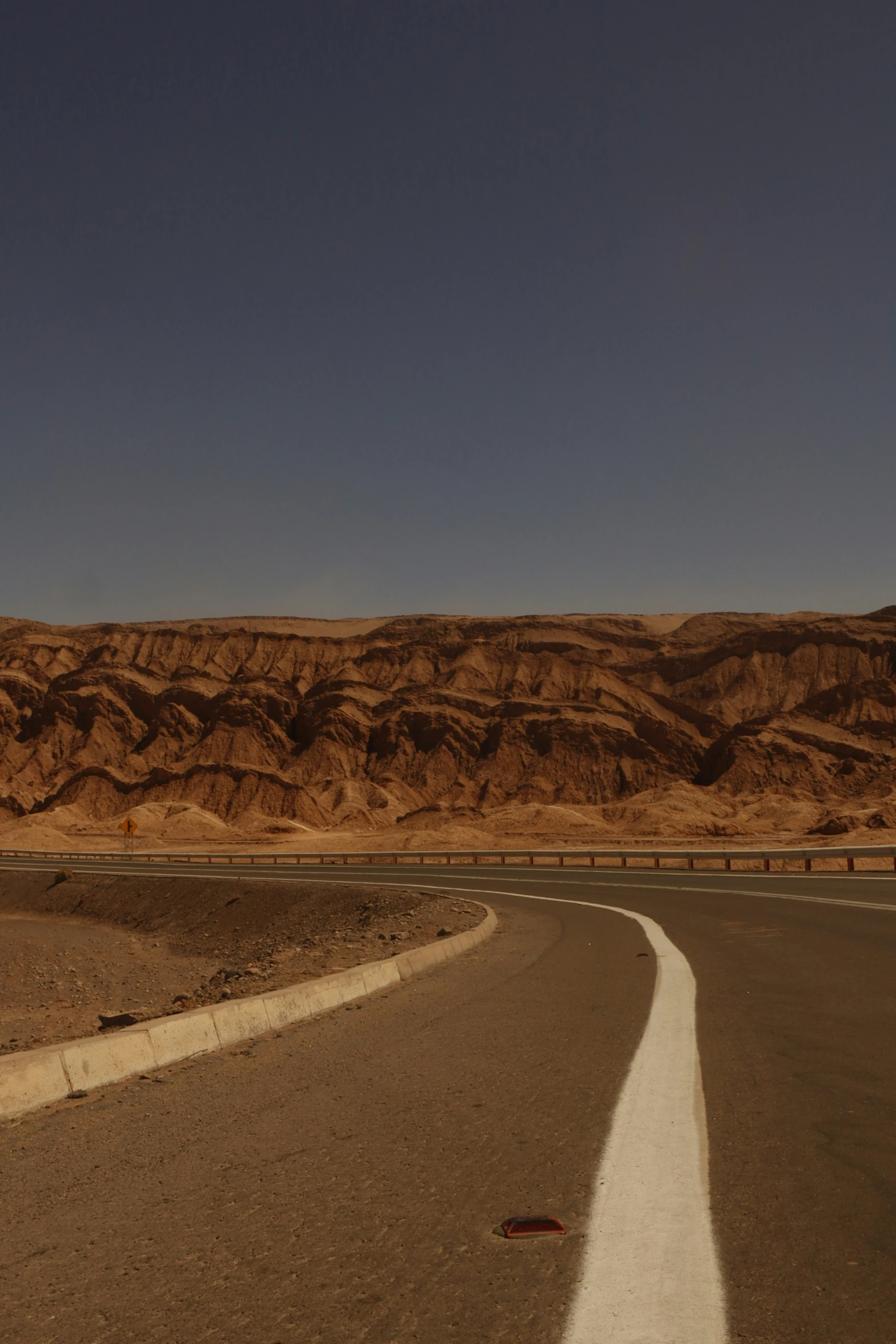 the empty street near the mountains with a no traffic sign