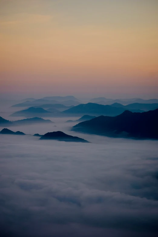 a mountain scene with low clouds, at dawn