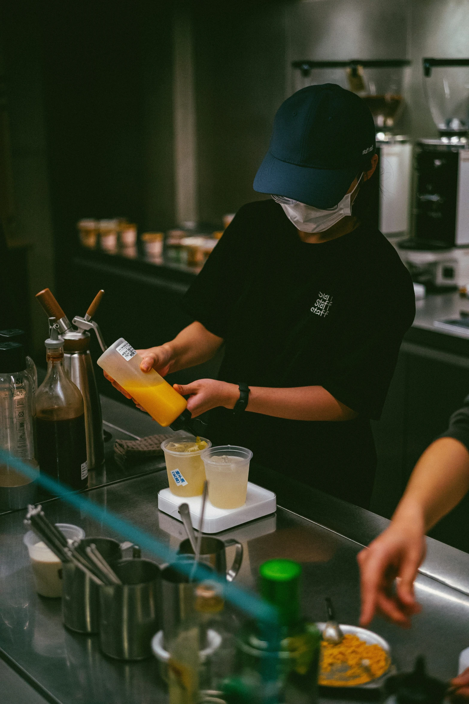 a man standing behind a counter making soing orange