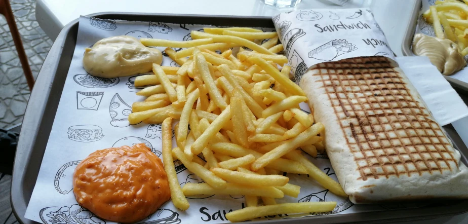 a meal containing french fries, cheese fries and a tomato