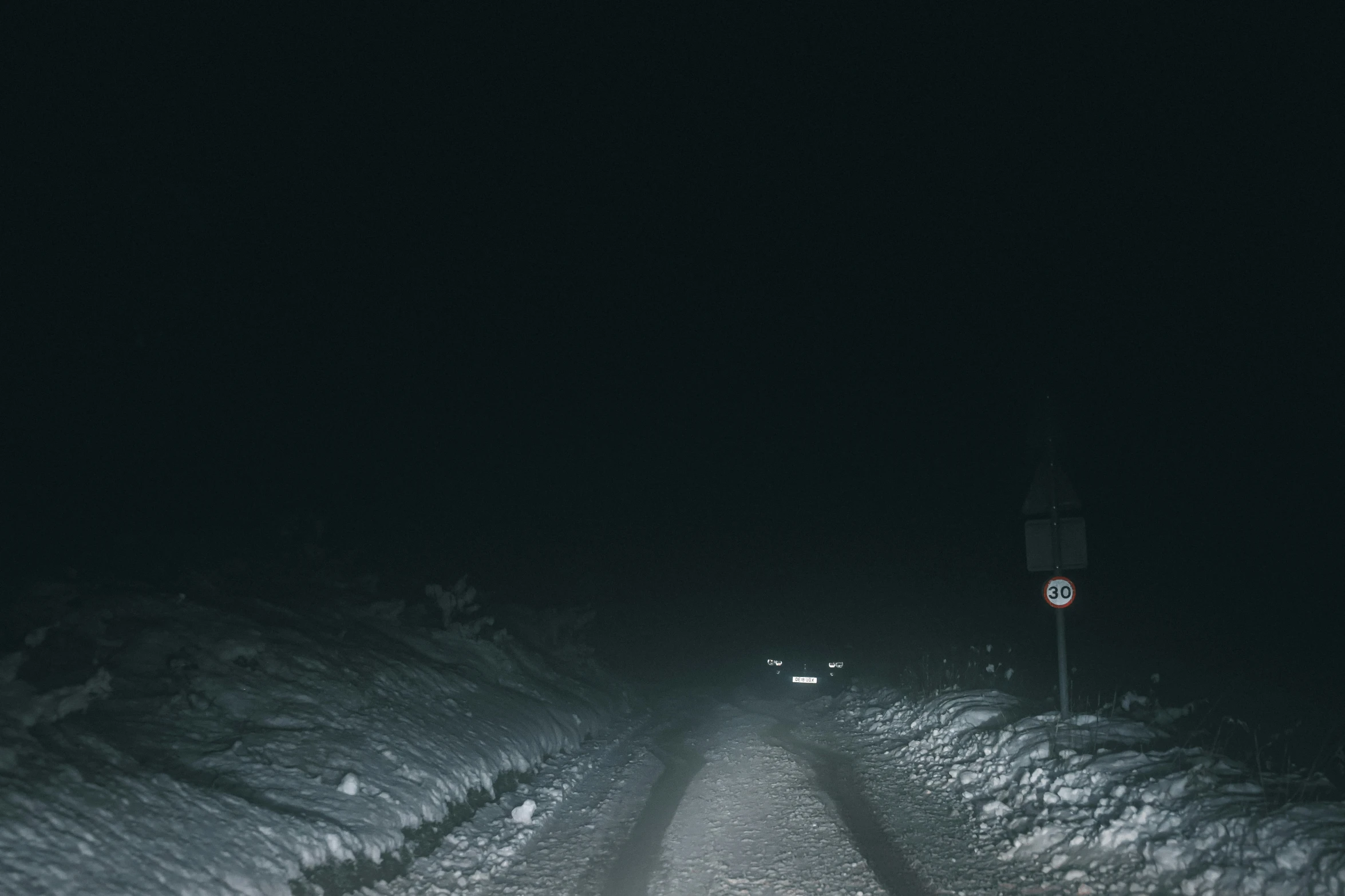 an eerie looking road at night covered in snow