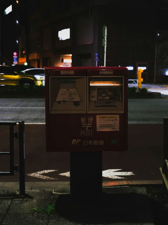 a red mail box sitting on the side of a street