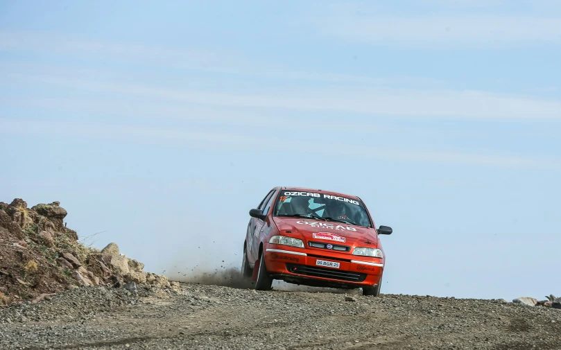 an orange car driving along a mountain side