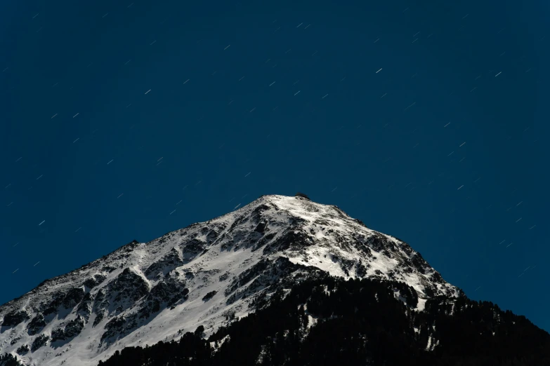 a snow capped mountain sits under the night sky