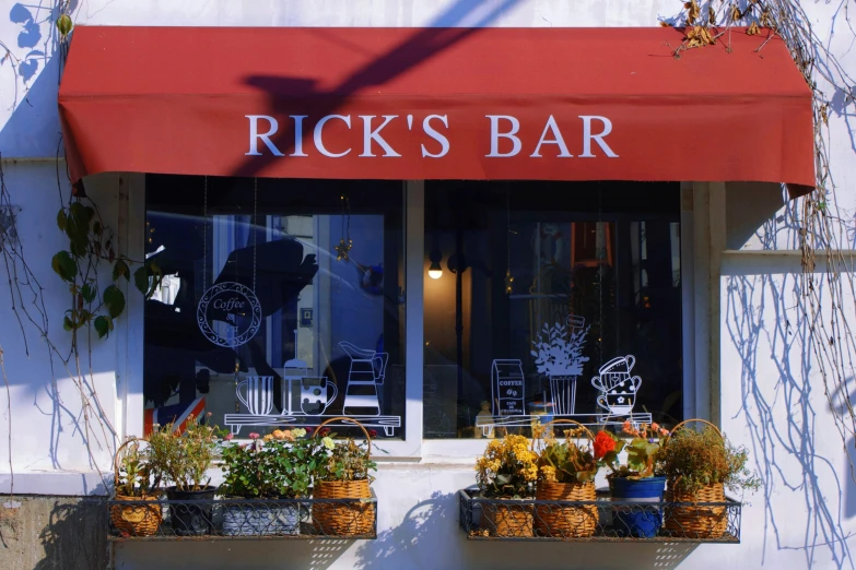 the outside of a restaurant with a red awning that says rick's bar