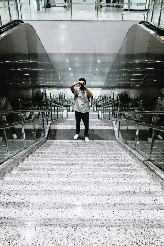 man standing on an escalator looking at his cellphone