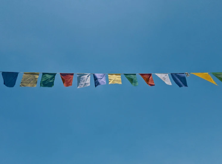 several multi - colored flags hanging under blue sky