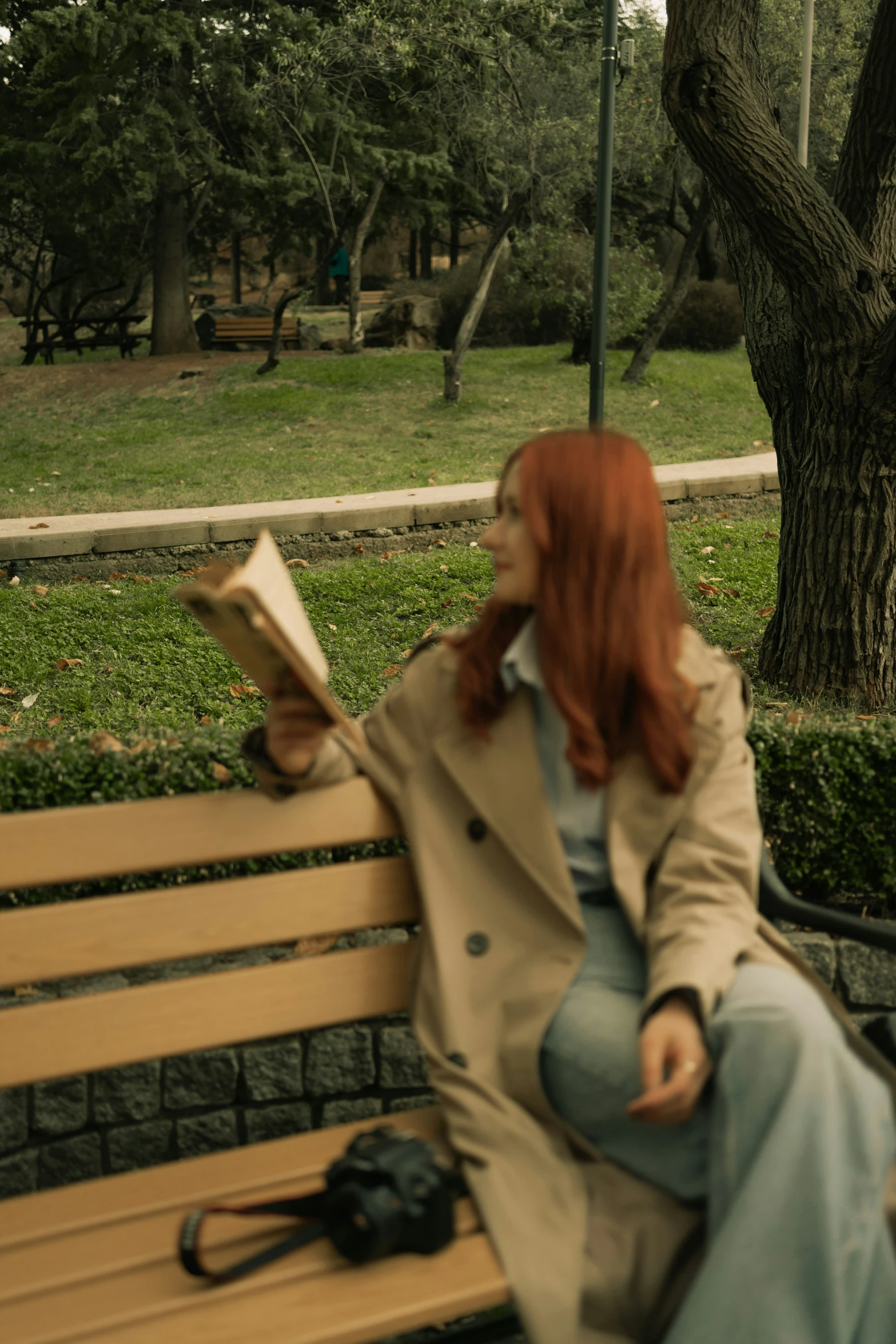 the woman with red hair is reading on the bench