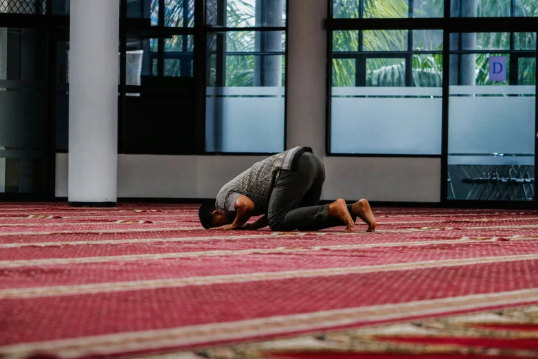 a woman kneeling on her stomach while praying in a lobby