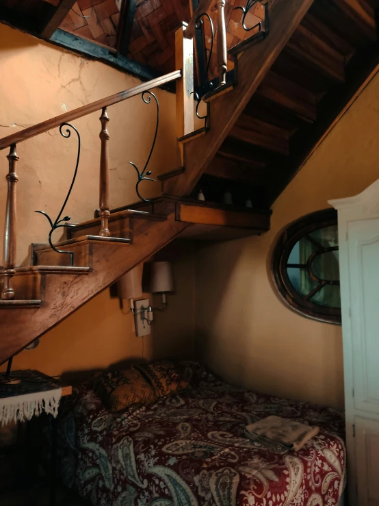 a bed under some stairs in a house