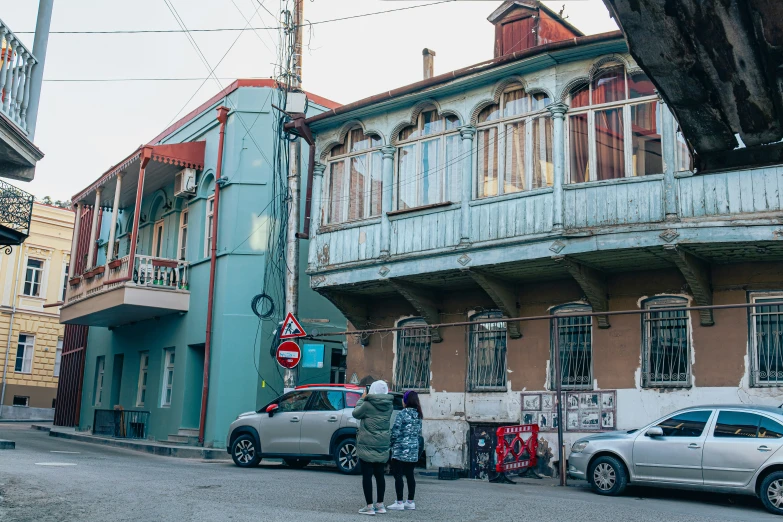 an old building with some people and cars parked on the street