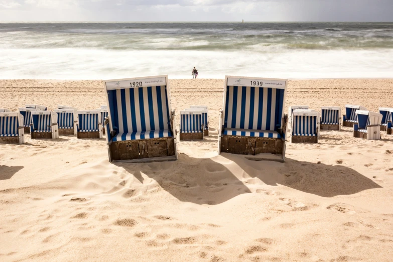 four lawn chairs facing the ocean on a beach