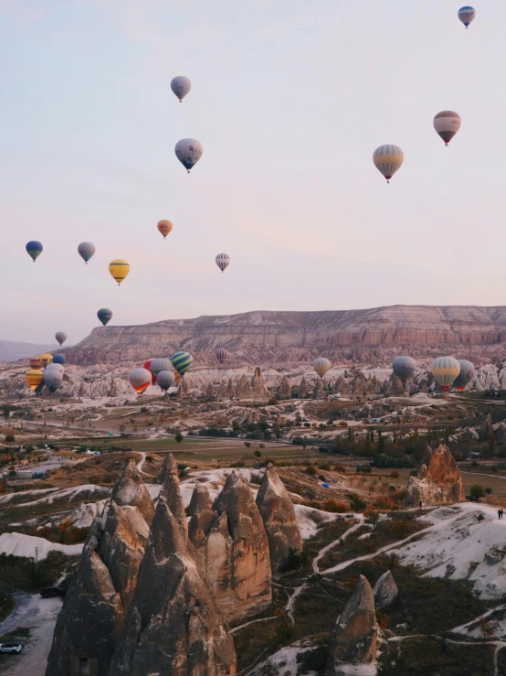 many balloons are flying in the sky over a mountain