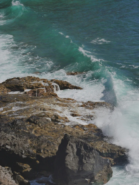 waves crash on the rocks next to a beach