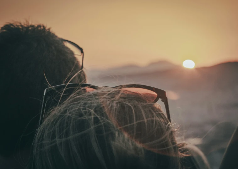 the back view of a woman and her husband from the top of a mountain at sunrise