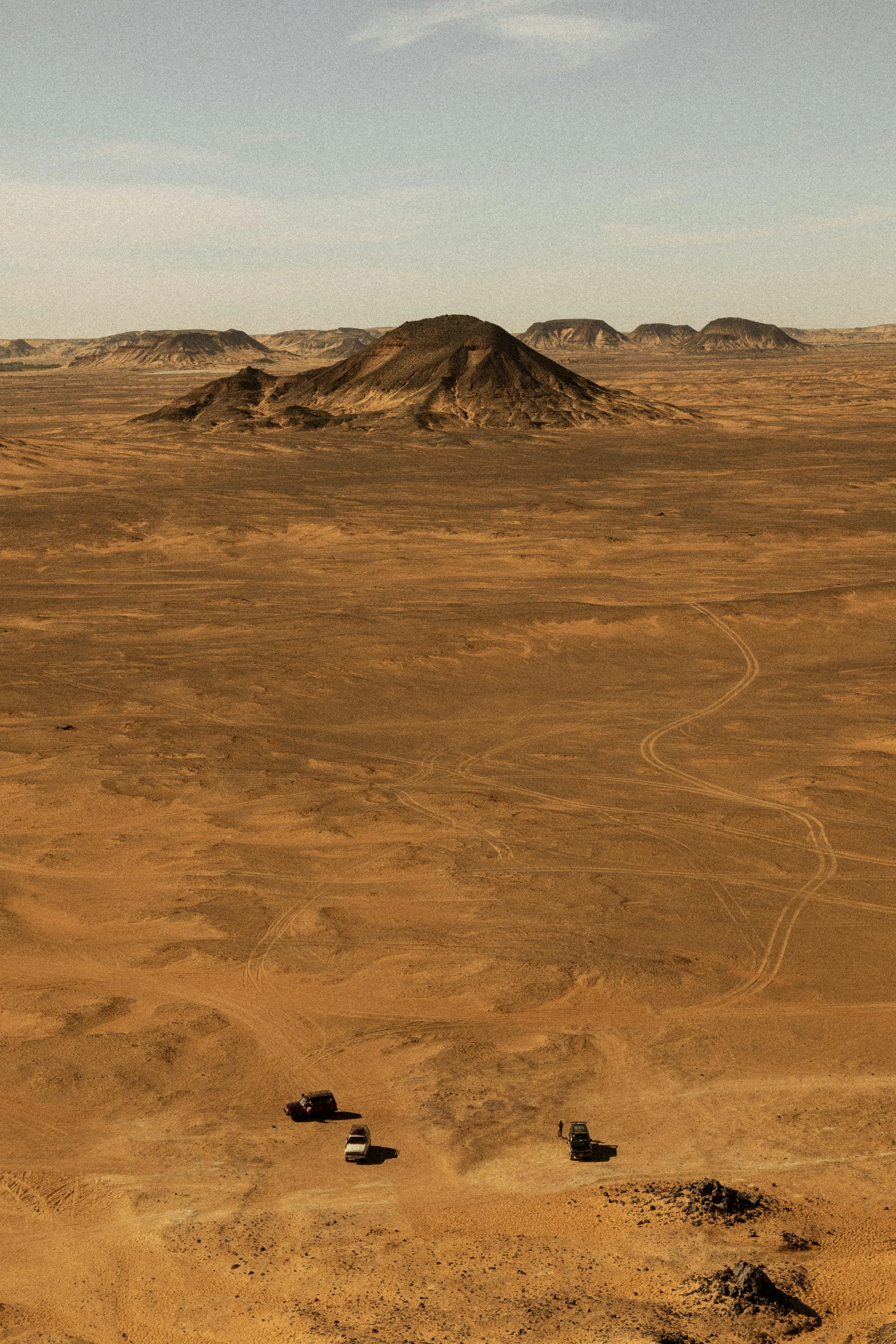 several dirt mounds and a mountain in the distance