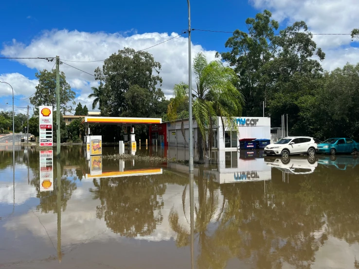 a car drives down the flooded street by an gas station