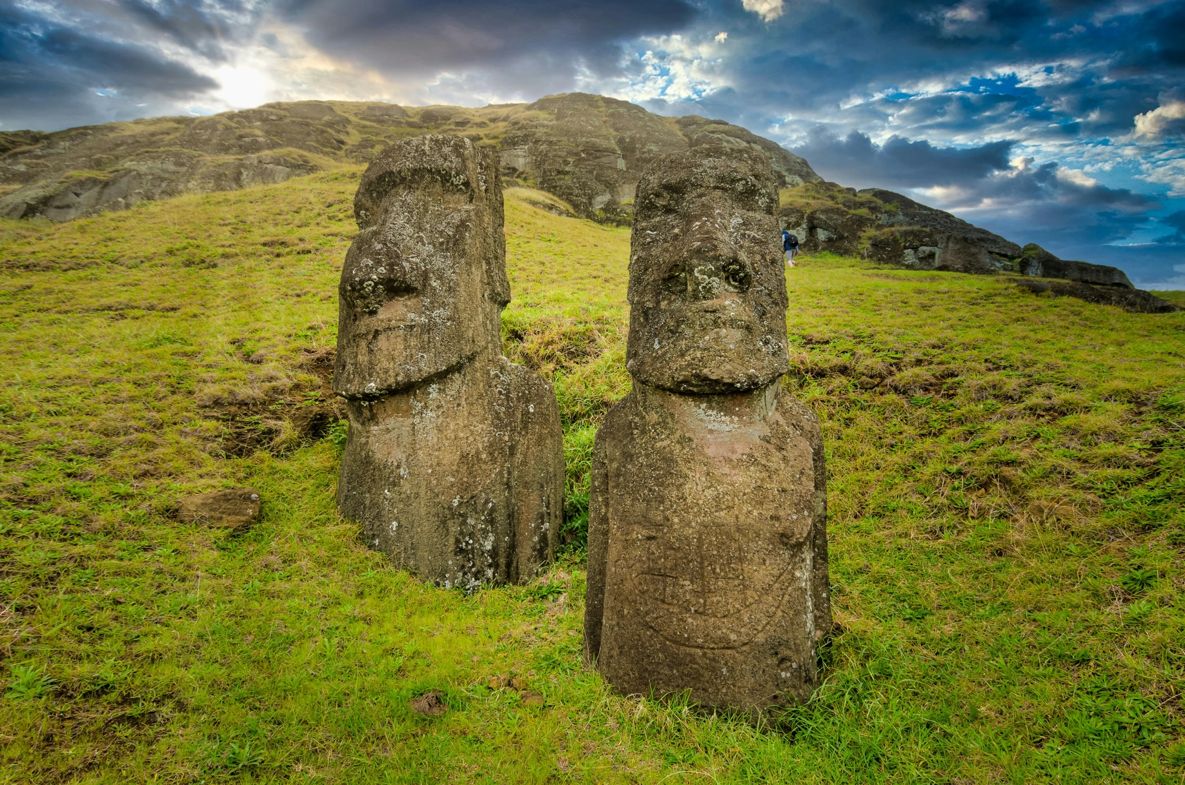 two statues in the grass near some rocks