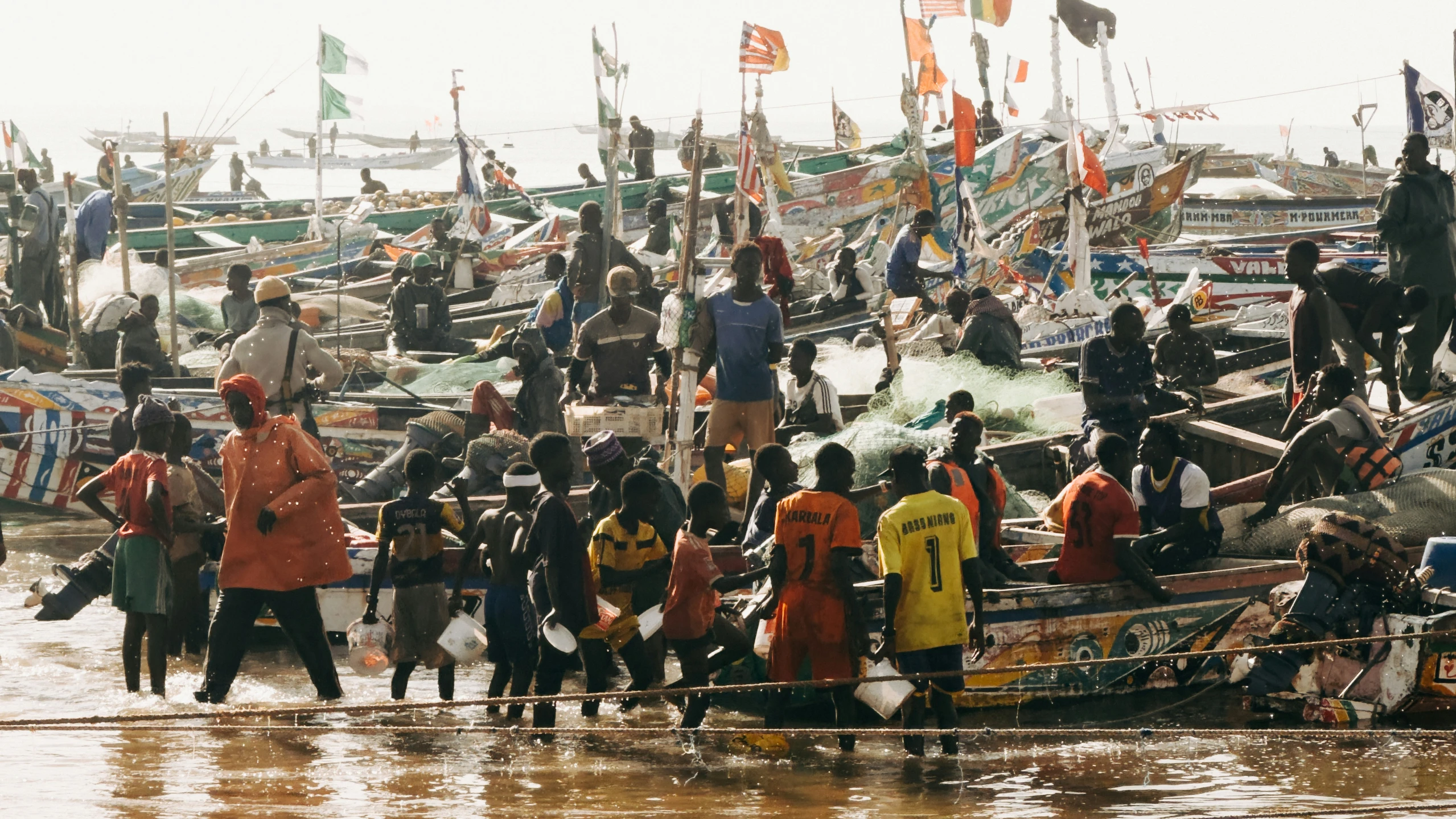 a bunch of people standing around some boats in the water