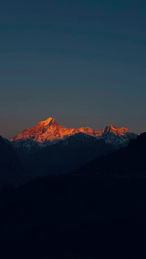 a snow covered mountain with a moon in the sky