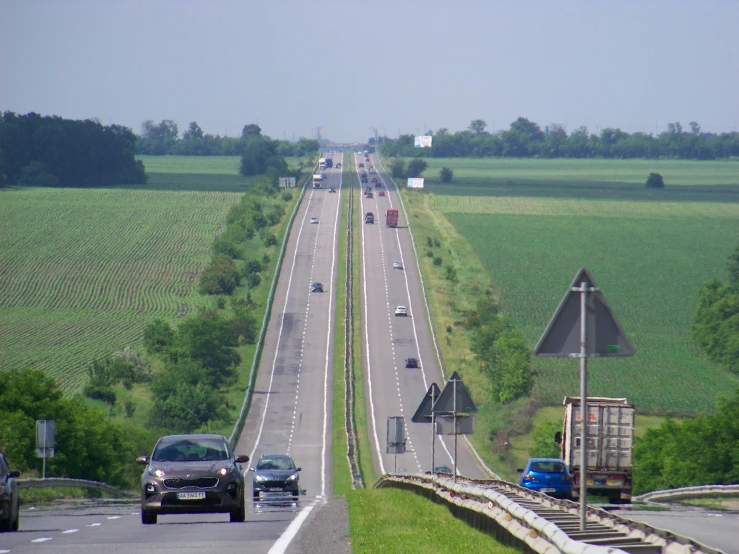 two cars driving down the road next to an interstate