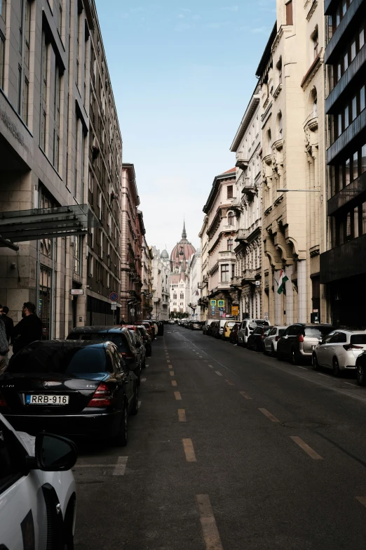 this is a city street with traffic on the roads and some people walking along the sidewalks