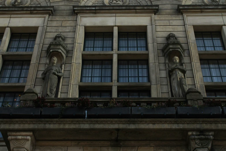 a tall building with many windows has statues on it