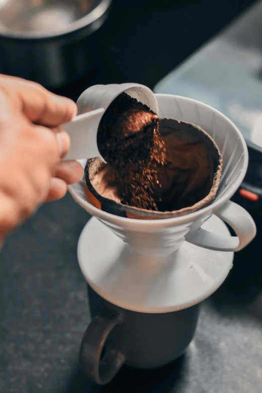 someone holds a spoon over some  chocolate in a white cup